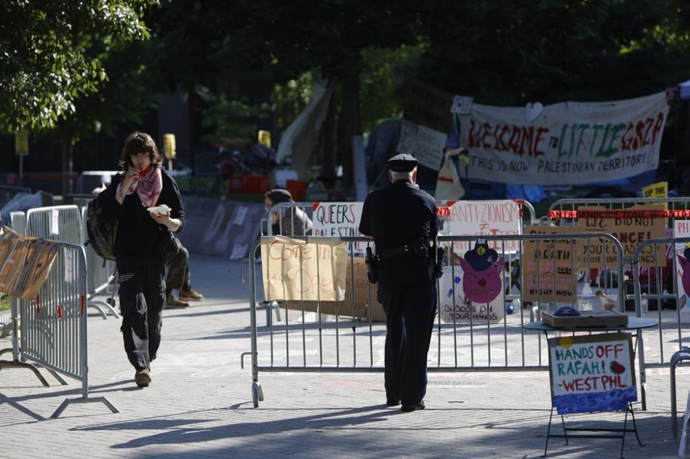 A police officer watches over the pro-Palestinian encampment at Drexel University, in Philadelphia, Wednesday, May 22, 2024. University administrators tried to open a line of communication to the protesters but were rebuffed, Drexel President John Fry said in a statement Tuesday. Lecture classes will remain virtual for a third day Wednesday because of the encampment, and some events will have to be rescheduled, Fry said. (Alejandro A. Alvarez/The Philadelphia Inquirer via AP)