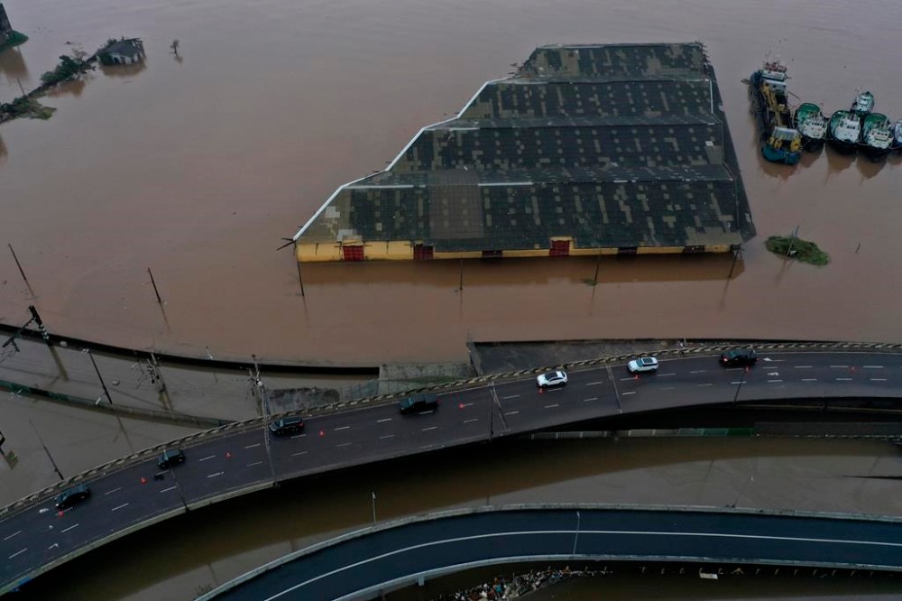 Vehicles travel along a lateral highway restored to allow the movement of humanitarian aid for those affected by floods caused by heavy rains, in Porto Alegre, Rio Grande do Sul state, Brazil, Saturday, May 11, 2024. (AP Photo/Wesley Santos)