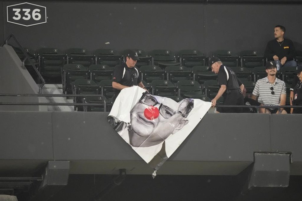 Security guards removes a sign portraying Chicago White Sox Chairman Jerry Reinsdorf as Bozo the Clown hangs from the 300 level of Guaranteed Rate Field during the eighth inning of a baseball game between the Chicago White Sox and the Baltimore Orioles Thursday, May 23, 2024, in Chicago. (AP Photo/Charles Rex Arbogast)