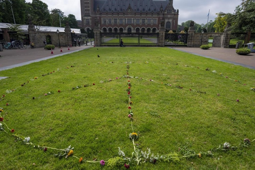 A Peace Sign is laid out with flowers outside the Peace Palace, office of the International Court of Justice, in The Hague, Netherlands, Thursday, May 16, 2024. The U.N.'s top court opened two days of hearings in a case brought by South Africa to see whether Israel needs to take additional measures to alleviate the suffering in war-ravaged Gaza. (AP Photo/Peter Dejong)