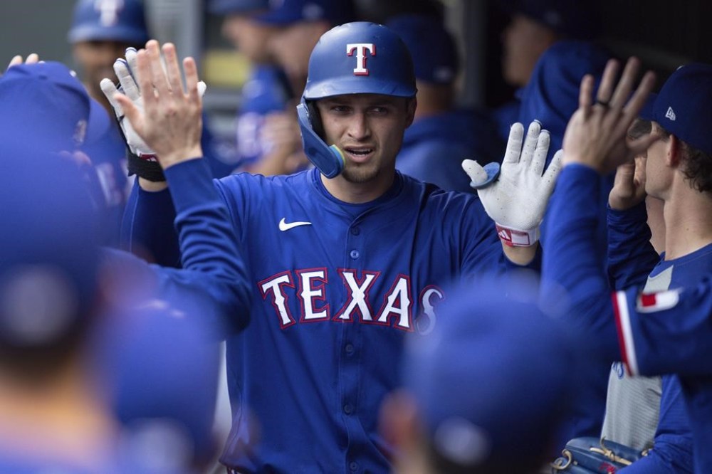 Texas Rangers' Corey Seager is congratulated in the dugout after his two-run home run against the Minnesota Twins during the first inning of a baseball game Friday, May 24, 2024, in Minneapolis. (AP Photo/Bailey Hillesheim)
