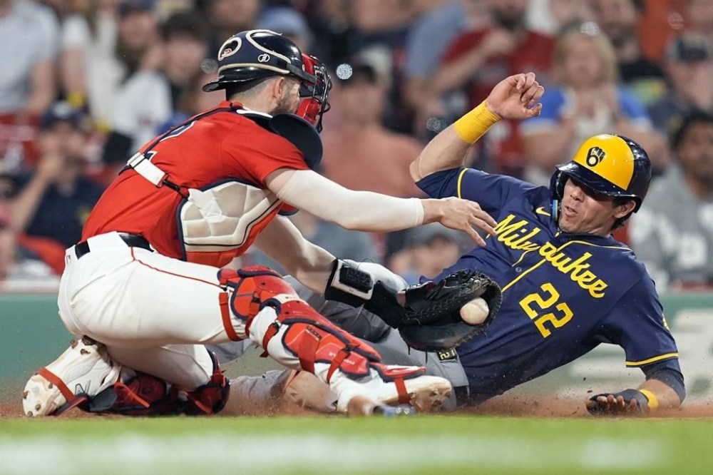 Milwaukee Brewers' Christian Yelich (22) beats a tag by Boston Red Sox catcher Connor Wong, left, as he scores on a sacrifice fly by Joey Ortiz during the ninth inning of a baseball game, Friday, May 24, 2024, in Boston. (AP Photo/Michael Dwyer)