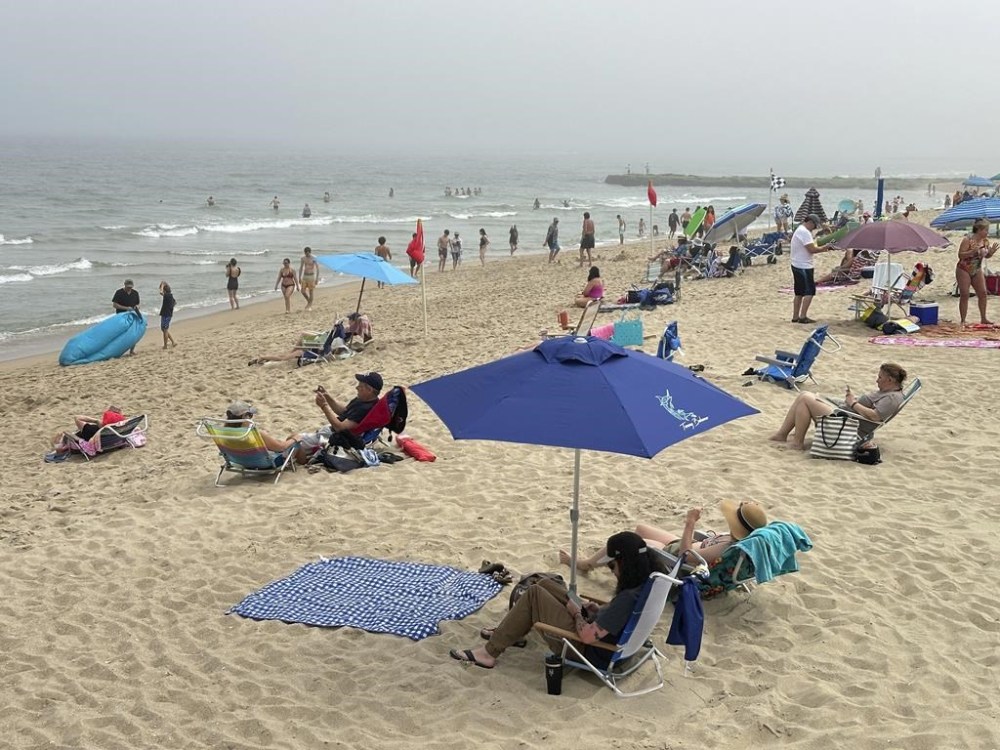 Beachgoers sit on chairs and under umbrellas at Ocean Grove, N.J., beach on Sunday, May 26, 2024. Beachgoers were out on the sand of one New Jersey shore community on a Sunday morning before Memorial day for the first time in generations amid a battle over a Christian religious group’s Sunday morning beach closures. (AP Photo/Tassanee Vejpongsa)