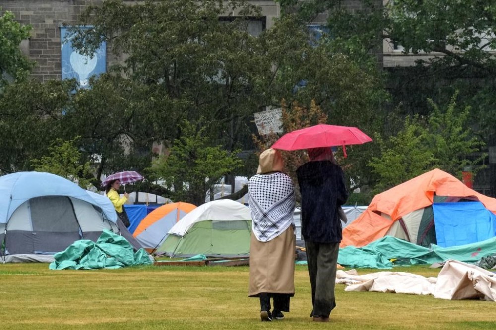 Supporters walk through the pro-Palestinian student encampment outside Convocation Hall on the University of Toronto campus, in Toronto, Monday, May 27, 2024. The University of Toronto is asking the courts to authorize police action to remove protesters who refuse orders to leave a pro-Palestinian encampment set up on campus earlier this month. THE CANADIAN PRESS/Chris Young