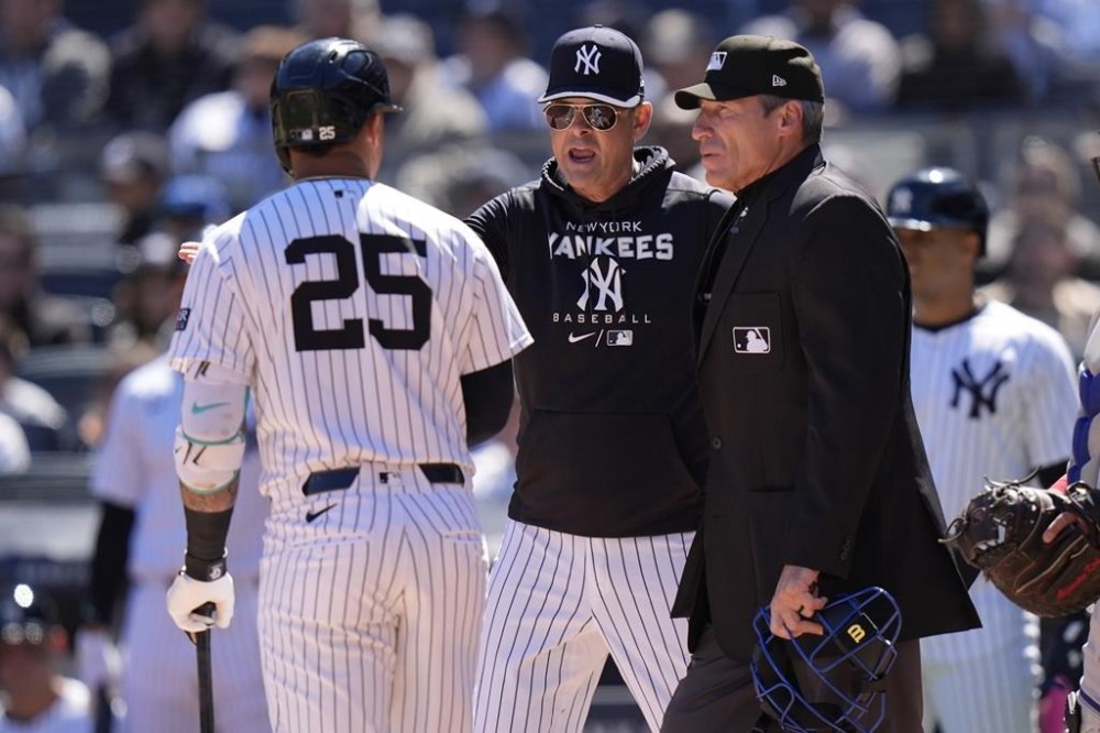 FILE - New York Yankees manager Aaron Boone, center, argues a call with umpire Angel Hernandez, right, as Gleyber Torres, left, watches during the first inning of a baseball game against the Toronto Blue Jays, April 7, 2024, in New York. Longtime umpire Hernández, who unsuccessfully sued Major League Baseball for racial discrimination, is retiring immediately, announced Monday, May 27, 2024. (AP Photo/Frank Franklin II, File)
