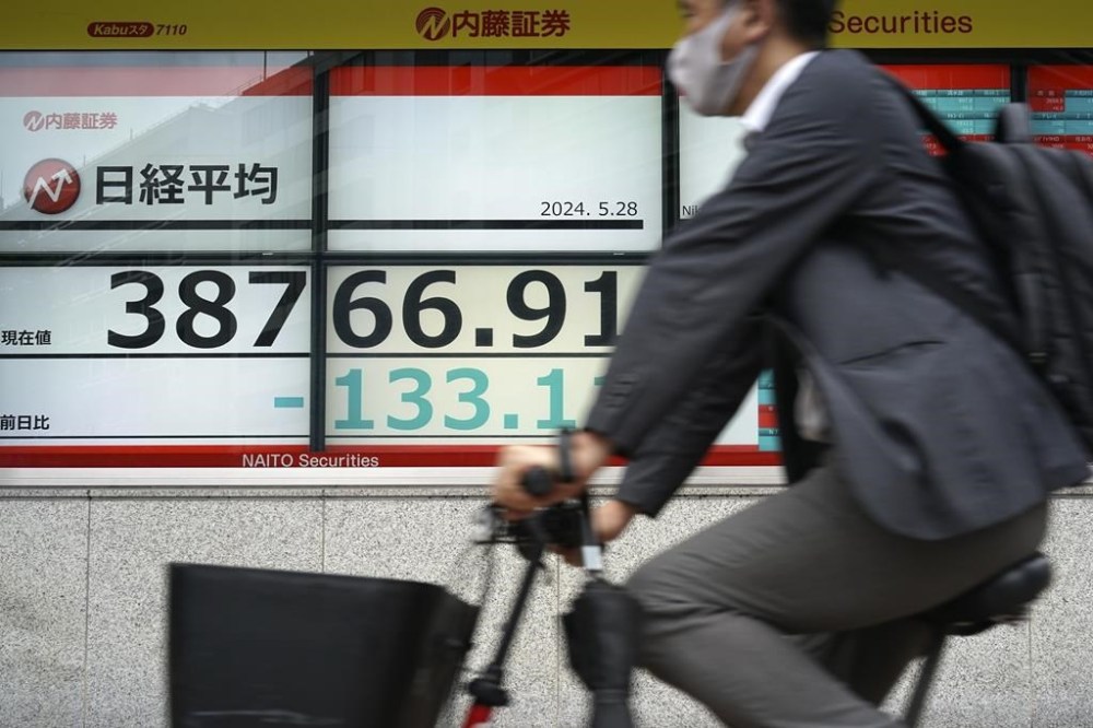 A person rides a bicycle in front of an electronic stock board showing Japan's Nikkei index at a securities firm Tuesday, May 28, 2024, in Tokyo. (AP Photo/Eugene Hoshiko)