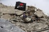 A picture of Hezbollah leader Sayyed Hassan Nasrallah sits on a house previously destroyed in an Israeli strike, in Aita al-Shaab village, south Lebanon, Monday, May 27, 2024. The Arabic on flag reads: 