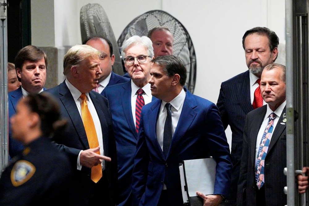 Former President Donald Trump speaks with his attorney Todd Blanche during in his trial, Tuesday, May 21, 2024, in Manhattan Criminal Court in New York. Looking on, from left are. U.S. Rep. Dale Strong, R-Ala. Texas Lt. Gov. Dan Patrick, radio host Sebastian Gorka and U.S. Rep. Troy Nehls, R-Texas. (Curtis Means/Dailymail.com via AP, Pool)