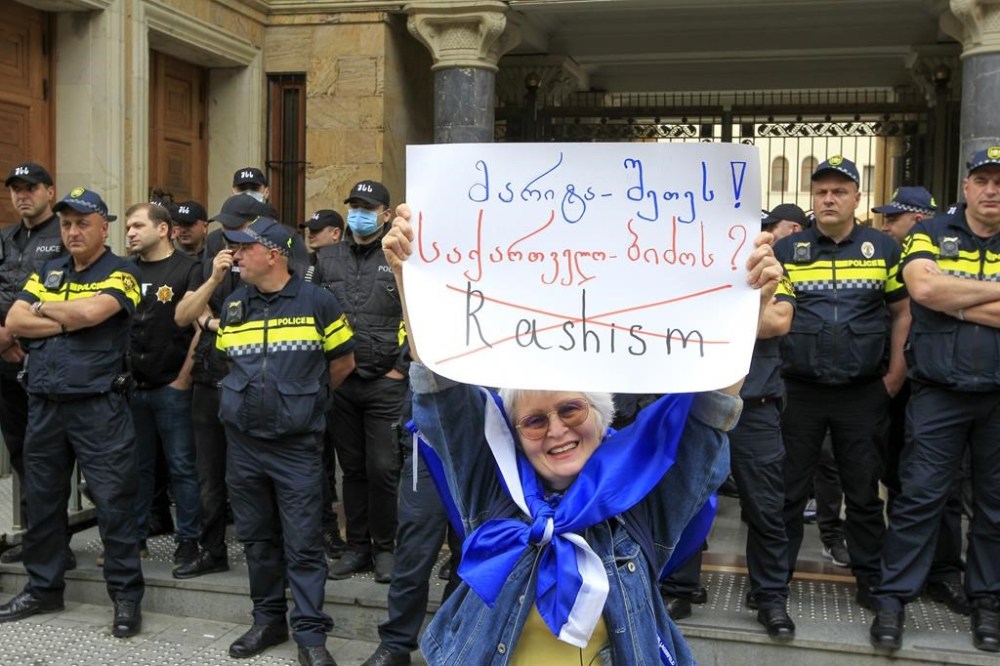 A demonstrators holds a poster in front of police during an opposition protest against the foreign influence bill at the Parliamentary building in Tbilisi, Georgia, Tuesday, May 28, 2024. (AP Photo/Shakh Aivazov)