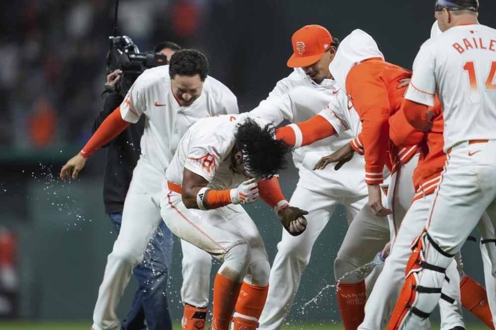 San Francisco Giants' Luis Matos, second from left, is mobbed by teammates after driving in the winning run with a sacrifice fly against the Philadelphia Phillies during the 10th inning of a baseball game Tuesday, May 28, 2024, in San Francisco. (AP Photo/Godofredo A. Vásquez)