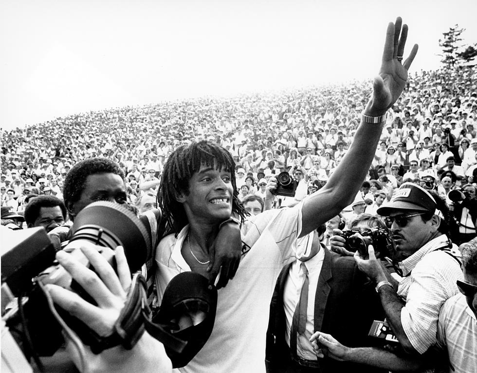 FILE - Yannick Noah of France, waves to the crowd at the Roland Garros stadium in Paris, June 5, 1983, after defeating Sweden's Mats Wilander to win the French Open men's singles tennis title. Yannick Noah, the 1983 French Open champion, will take over as captain of Team Europe in the Laver Cup in 2025, replacing Bjorn Borg. The event announced Noah’s position Wednesday May 29, 2024. (AP Photo/Jacques Langevin, File)