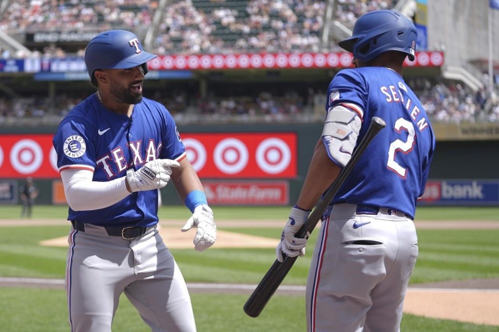Texas Rangers' Ezequiel Duran, left, celebrates with Marcus Semien (2) after hitting a solo home run during the fifth inning of a baseball game against the Minnesota Twins, Saturday, May 25, 2024, in Minneapolis. (AP Photo/Abbie Parr)