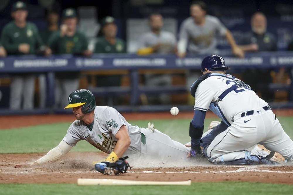 Oakland Athletics' Max Schuemann scores as Tampa Bay Rays catcher Alex Jackson can't handle the throw during the eighth inning of a baseball game Wednesday, May 29, 2024, in St. Petersburg, Fla. (AP Photo/Mike Carlson)