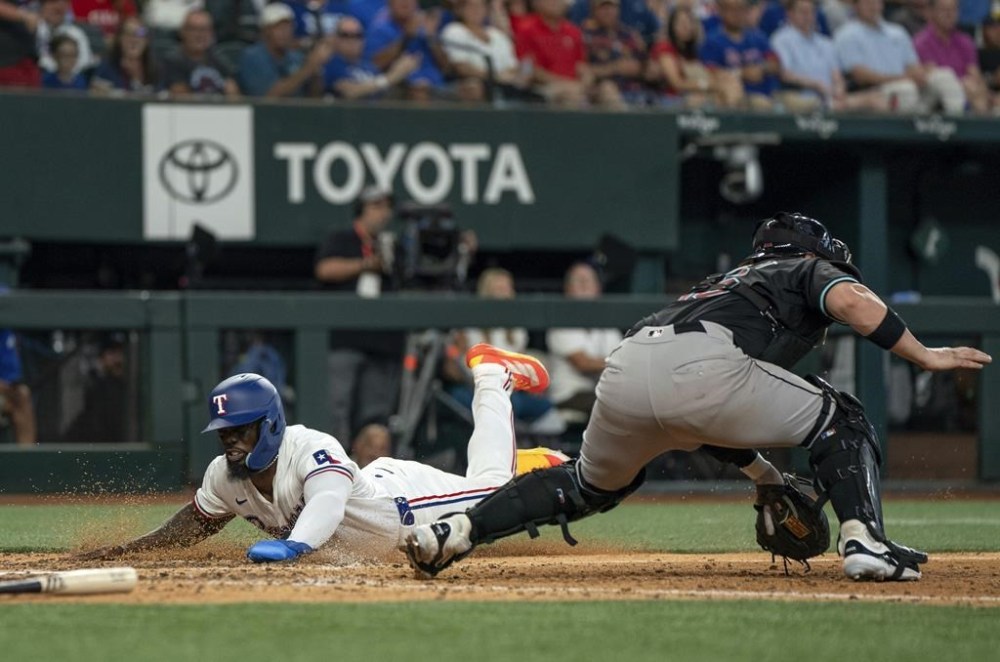 Texas Rangers' Adolis García scores in front of Arizona Diamondbacks catcher Tucker Barnhart on a single by Wyatt Langford during the eighth inning of a baseball game Wednesday, May 29, 2024, in Arlington, Texas. (AP Photo/Jeffrey McWhorter)
