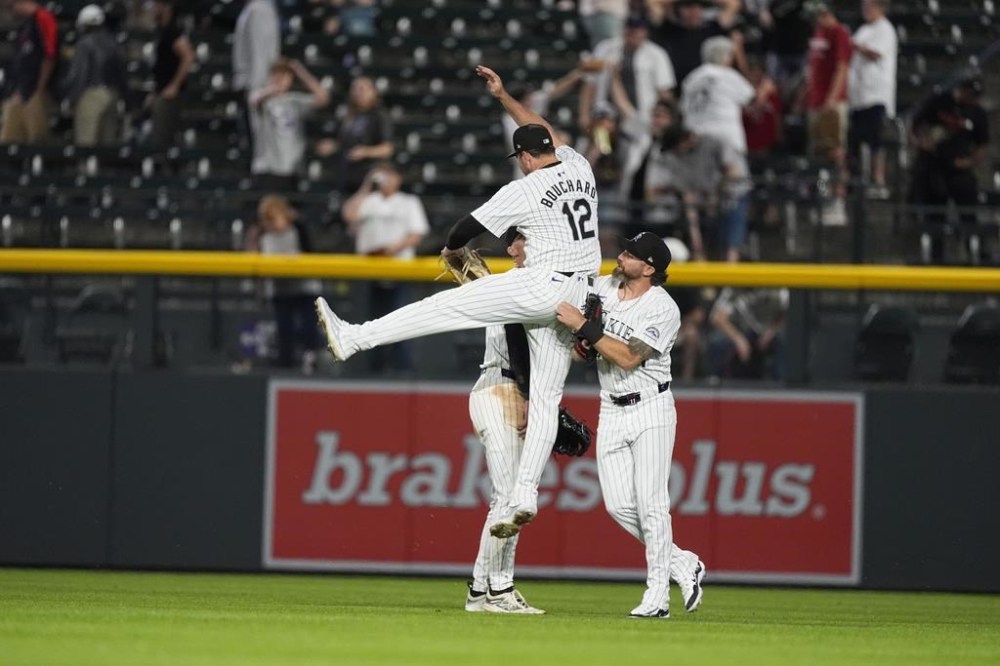 Colorado Rockies left fielder Sean Bouchard (12) celebrates with center fielder Brenton Doyle, back left, and right fielder Jake Cave after the team's baseball game against the Cleveland Guardians on Wednesday, May 29, 2024, in Denver. (AP Photo/David Zalubowski)