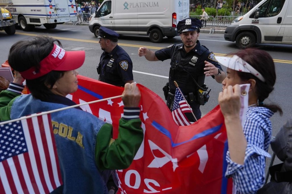 People gather outside Manhattan Criminal Court to watch former President Donald Trump's motorcade to pass after the guilty verdict announced against Trump, Thursday, May 30, 2024, in New York. Donald Trump became the first former president to be convicted of felony crimes as a New York jury found him guilty of 34 felony counts of falsifying business records in a scheme to illegally influence the 2016 election through hush money payments to a porn actor who said the two had sex. (AP Photo/Julia Nikhinson)