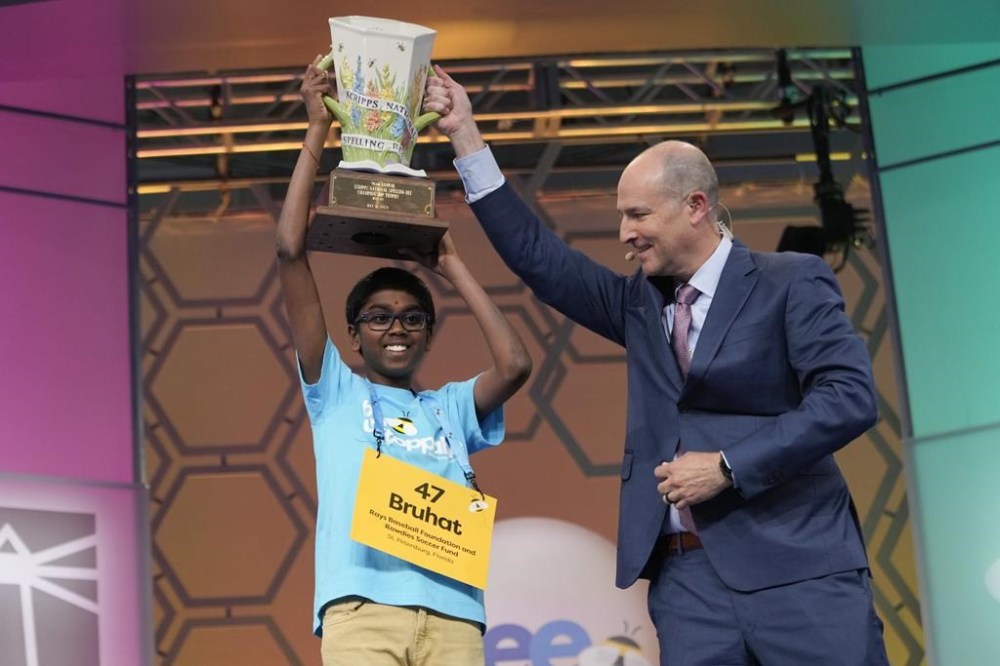 Bruhat Soma, 12, of Tampa, Fla., accepts the trophy from E.W. Scripps Company president and CEO Adam Symson after winning the Scripps National Spelling Bee, in Oxon Hill, Md., Thursday, May 30, 2024. (AP Photo/Jacquelyn Martin)