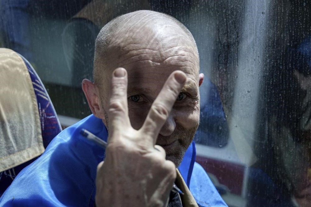 A Ukrainian serviceman shows the victory sign after returning from captivity during POWs exchange in Sumy region, Ukraine, Friday, May 31, 2024. Ukraine returned 75 prisoners, including four civilians, in the latest exchange of POWs with Russia. It's the fourth prisoner swap this year, and 52nd since Russia invaded Ukraine. In all, 3 210 Ukrainian servicemen and civilians were returned since the outbreak of the war. (AP Photo/Evgeniy Maloletka)
