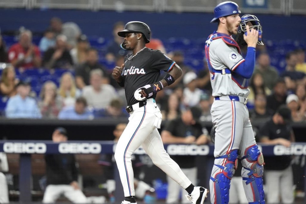 Miami Marlins' Jazz Chisholm Jr., left, scores past Texas Rangers catcher Jonah Heim, right, during the third inning of a baseball game, Friday, May 31, 2024, in Miami. (AP Photo/Lynne Sladky)