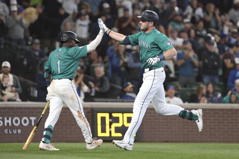 Seattle Mariners' Luke Raley, right, crosses home plate and celebrates with Ryan Bliss after hitting a home run off Los Angeles Angels pitcher Carson Fulmer during the sixth inning of a baseball game Saturday, June 1, 2024, in Seattle. (AP Photo/Jason Redmond)