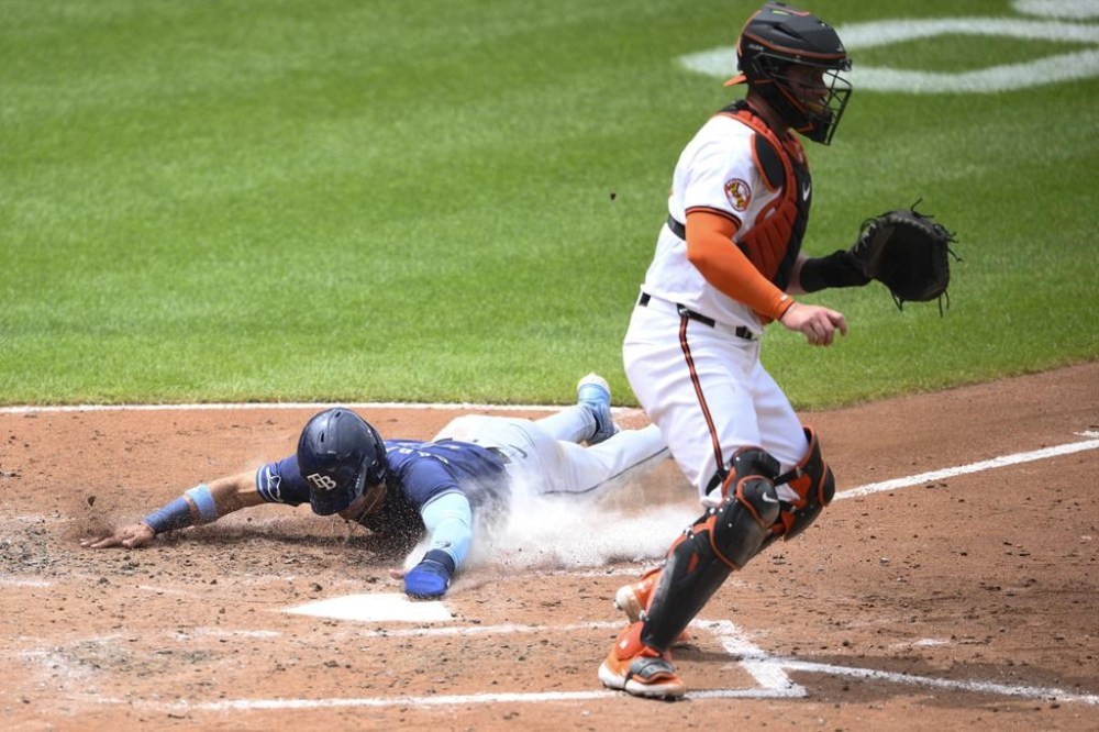 Tampa Bay Rays' Jose Caballero, left, slides home to score against Baltimore Orioles catcher James McCann, right, on a sacrifice fly by Yandy Diaz during the fifth inning of a baseball game, Sunday, June 2, 2024, in Baltimore. (AP Photo/Nick Wass)