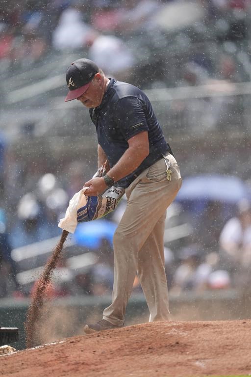 A member of the Atlanta Braves grounds crew works to dry the pitchers mound during a rain shower in the sixth inning of a baseball game between Atlanta Braves and Oakland Athletics Sunday, June 2, 2024, in Atlanta. (AP Photo/John Bazemore)