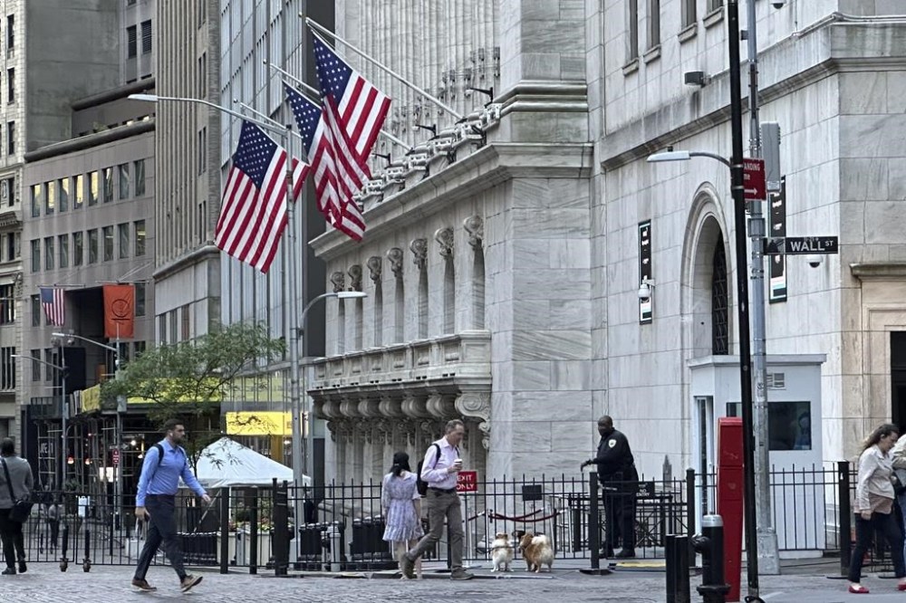 FILE - People pass the New York Stock Exchange on Wednesday, May 29, 2024, in New York. Some U.S. companies saw the trading of their shares temporarily halted Monday, June 3, including at least one whose price briefly fell nearly 100%, following a technical issue for some stocks listed on the New York Stock Exchange. (AP Photo/Peter Morgan, File)