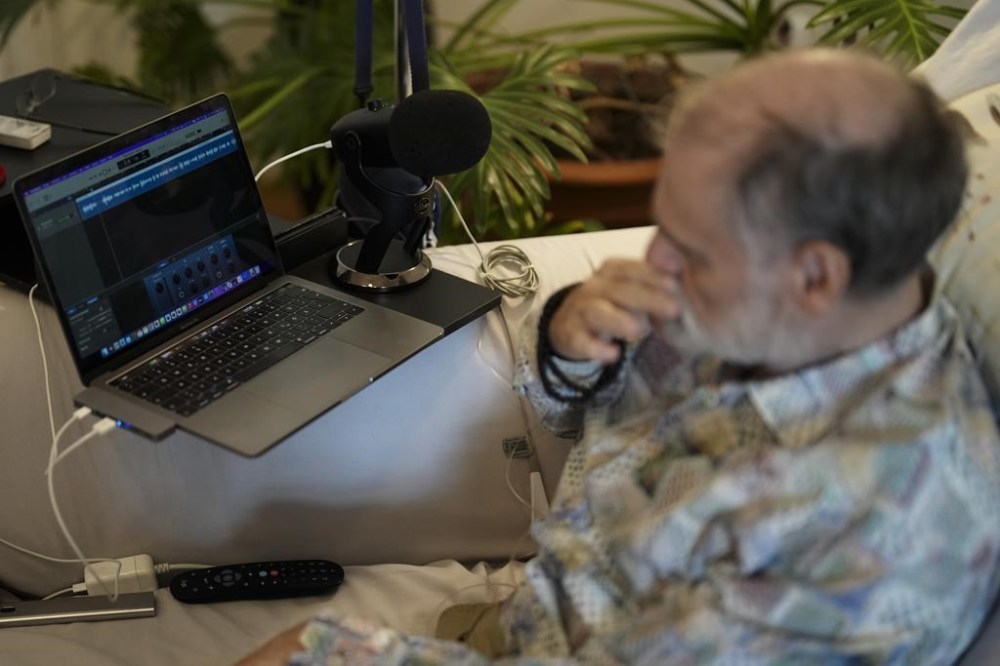 Michael Bommer, who is terminally ill with colon cancer, listens to his AI generated voice during a meeting with The Associated Press at his home in Berlin, Germany, Wednesday, May 22, 2024. Bommer, who has only a few more weeks to live, teamed up with friend who runs the AI-powered legacy platform Eternos to