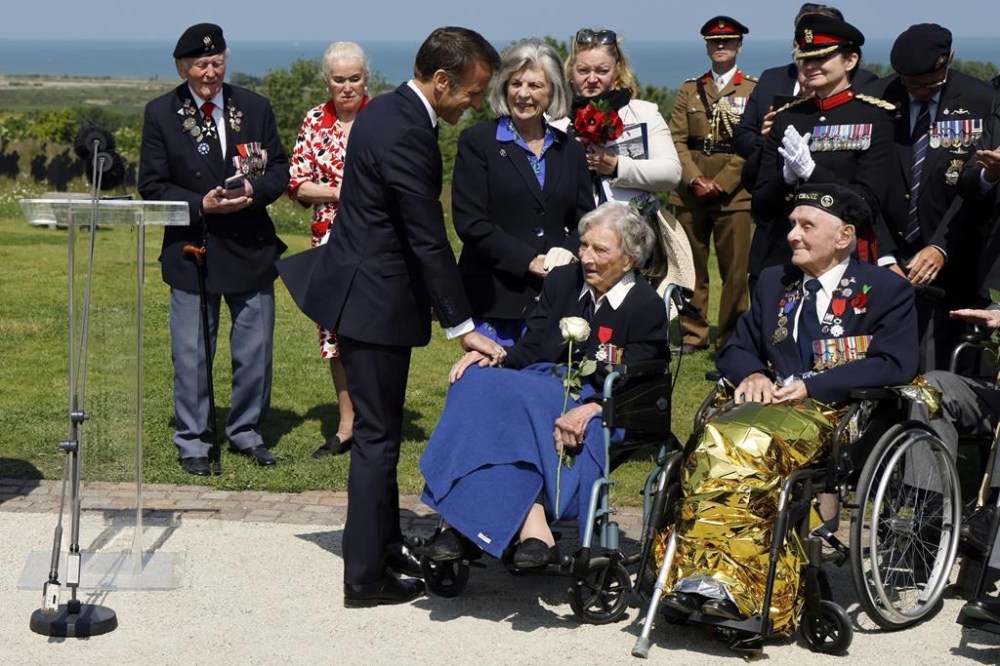 France's President Emmanuel Macron reacts after awarding 104-years-old British World War II veteran Christian Lamb, center, who helped to plan the D-Day landings in Normandy, with the insignia of Knight in the Legion of Honor order, during a commemorative ceremony marking the 80th anniversary of the World War II D-Day Allied landings in Normandy, at the World War II British Normandy Memorial of Ver-sur-Mer, Thursday, June 6, 2024. Normandy is hosting various events to officially commemorate the 80th anniversary of the D-Day landings that took place on June 6, 1944. (Ludovic Marin/Pool via AP)