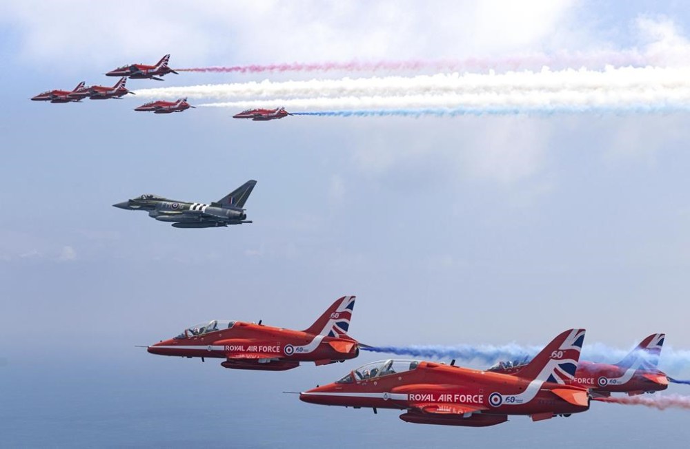 The Royal Air Force Aerobatic Team (RAFAT), the 'Red Arrows', accompanied by Typhoon Display Team 'Moggy' aircraft fly over the British Normandy Memorial, during a major commemorative event in Normandy to mark the 80th Anniversary of D-Day, in Ver-sur-Mer, France, Thursday June 6, 2024. (Cpl Phil Dye/Ministry of Defence via AP)
