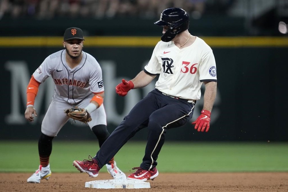 Texas Rangers' Wyatt Langford reaches for a double as San Francisco Giants second baseman Thairo Estrada looks on in the fifth inning of a baseball game, Friday, June 7, 2024, in Arlington, Texas. (AP Photo/Tony Gutierrez)