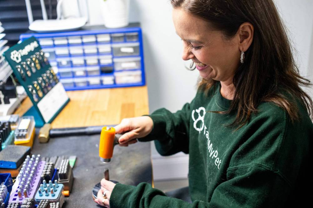 Melissa Le-Fort stamps custom-made pet identification tags in her home studio. (Mikaela MacKenzie / Free Press)