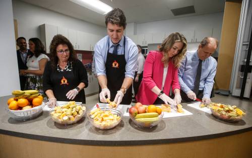 Kim Jemielity, educational assistant (from left), Prime Minister Justin Trudeau, Jenna Sudds, Minister of Families, Children and Social Development, and MP Kevin Lamoureux prepare food for students at a food program at Elwick Community School in Winnipeg, Friday. (John Woods / The Canadian Press)