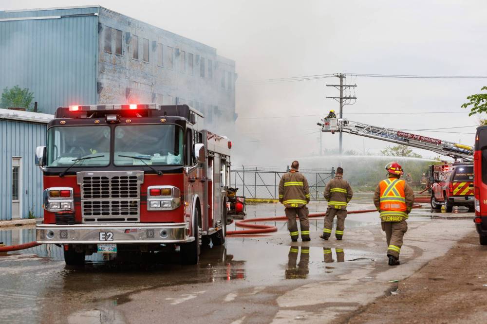 Winnipeg Fire Paramedic Service crews work at putting out a fire as smoke billows from a large building on Logan Avenue. (Mike Deal / Free Press)