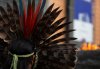 A leader of an indigenous community in Brazil wears a feather headdress as he protests against forest destruction in front of a burning log outside the EU headquarters in Brussels, Tuesday, Nov. 5, 2019. Demonstrator on Tuesday were demanding that EU and national leaders act to stop the forest destruction and related human rights abuses in the Amazon, Cerrado, Pantanl and Mata Atlantica. (AP Photo/Virginia Mayo)