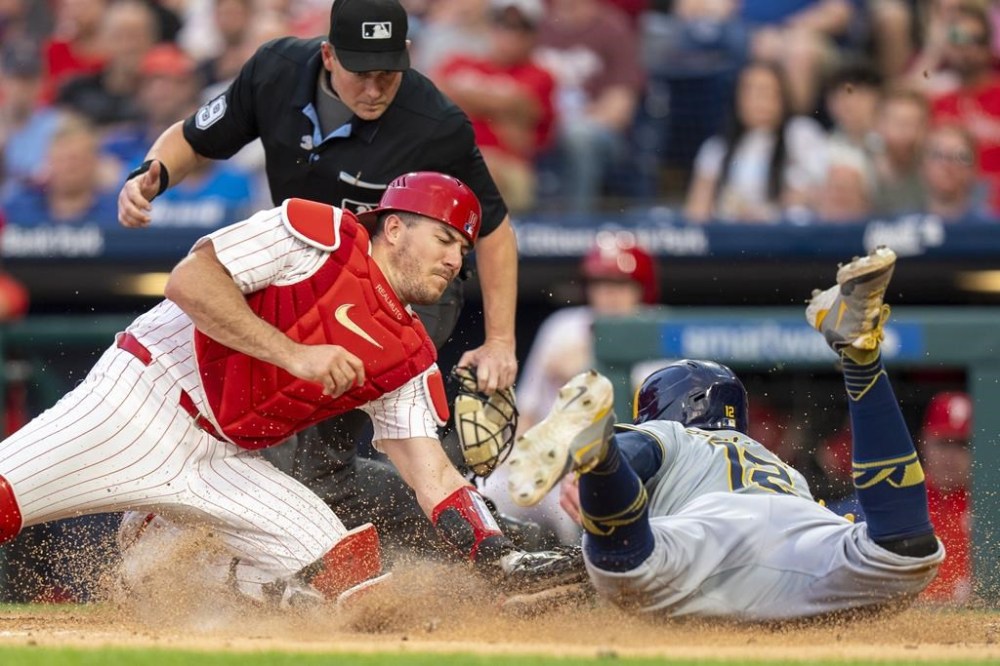 Philadelphia Phillies catcher J.T. Realmuto, front left, tags out Milwaukee Brewers' Rhys Hoskins, right, during the fifth inning of a baseball game, Monday, June 3, 2024, in Philadelphia. (AP Photo/Chris Szagola)