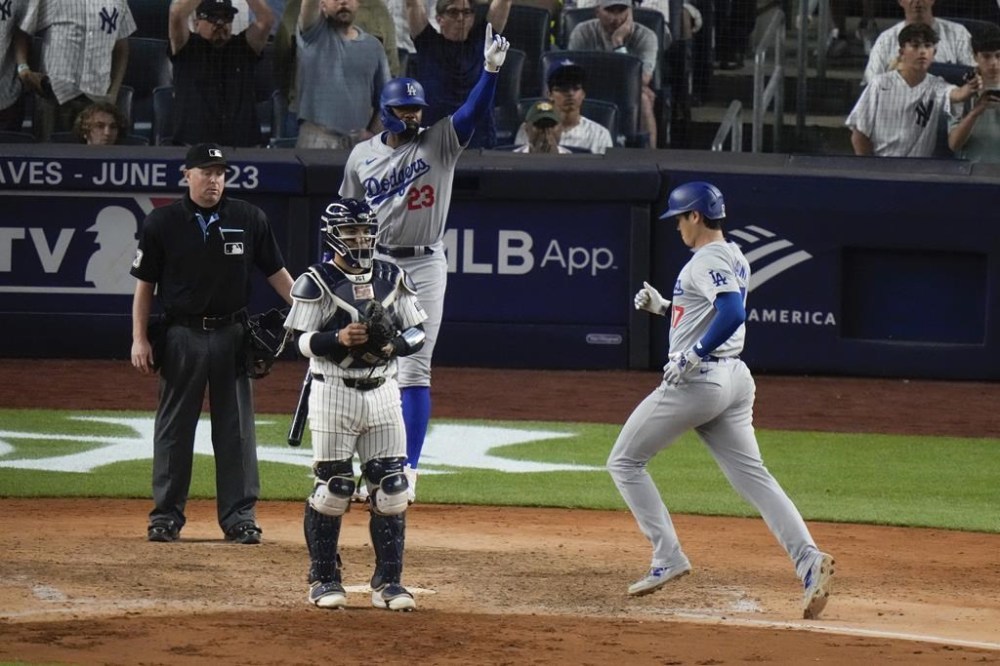 Los Angeles Dodgers' Jason Heyward (23) celebrates as Shohei Ohtani, of Japan, runs to home plate to score on a two-run double by Teoscar Hernández as New York Yankees catcher Jose Trevino watches during the eleventh inning of a baseball game, Friday, June 7, 2024, in New York. (AP Photo/Frank Franklin II)