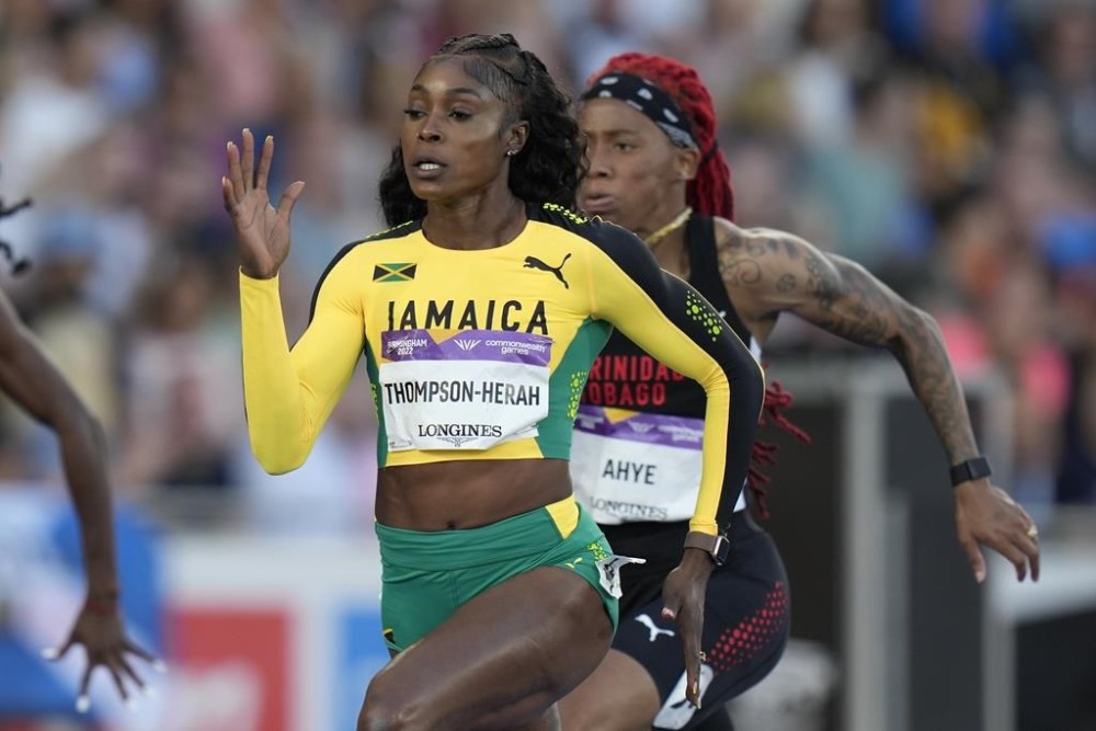 FILE - Jamaica's Elaine Thompson-Herah, center, races to win a women's 100m semifinal during the athletics in the Alexander Stadium at the Commonwealth Games in Birmingham, England, Wednesday, Aug. 3, 2022. Is trying to join Usain Bolt as only the second person to win three straight gold medals at both 100 and 200 meters. (AP Photo/Alastair Grant, File)