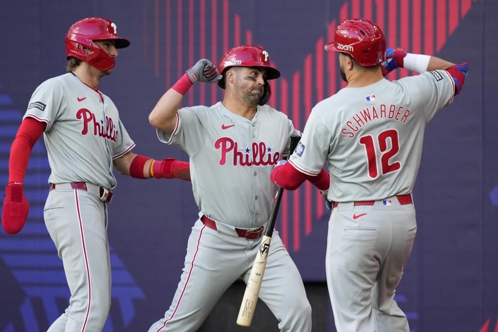 Philadelphia Phillies' Whit Merrifield, center, celebrates after hitting a 3-run home run against the New York Mets during the fourth inning of a London Series baseball game in London, Saturday, June 8, 2024. (AP Photo/Kirsty Wigglesworth)