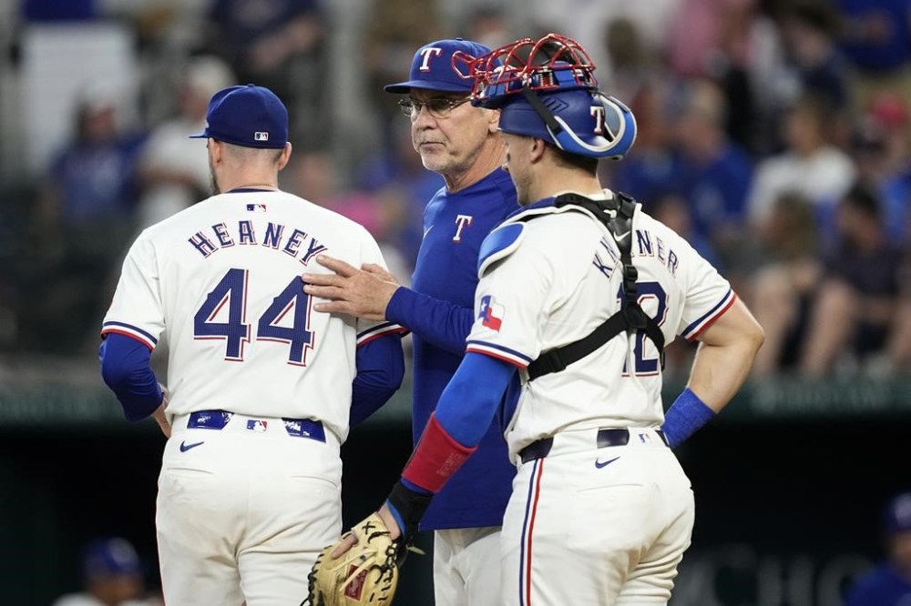 Texas Rangers manager Bruce Bochy, center, takes the ball from starter Andrew Heaney (44) as catcher Andrew Knizner, right, stands by in the sixth inning of a baseball game against the San Francisco Giants, Saturday, June 8, 2024, in Arlington, Texas. (AP Photo/Tony Gutierrez)