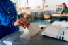 A woman in a European hoodie throws her ballot paper into the ballot box for the European elections at a polling station in Frankfurt, Germany Sunday, June 9, 2024. (Andreas Arnold/dpa via AP)