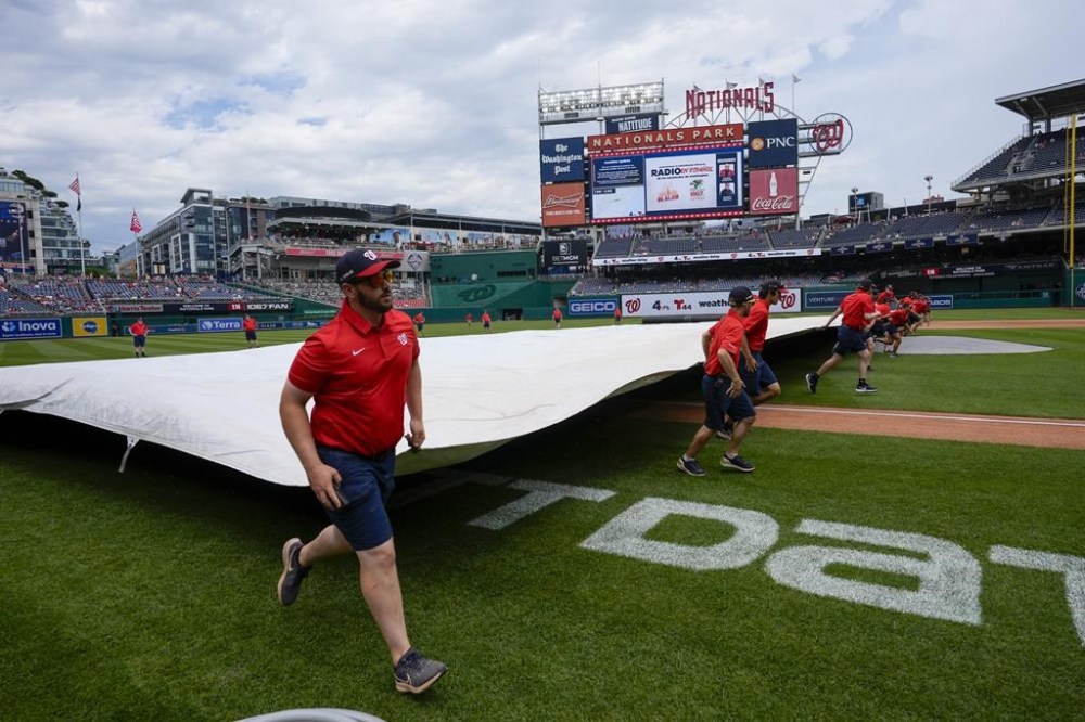 The grounds crew covers the field before a baseball game between the Washington Nationals and the Atlanta Braves at Nationals Park, Sunday, June 9, 2024, in Washington. (AP Photo/Alex Brandon)