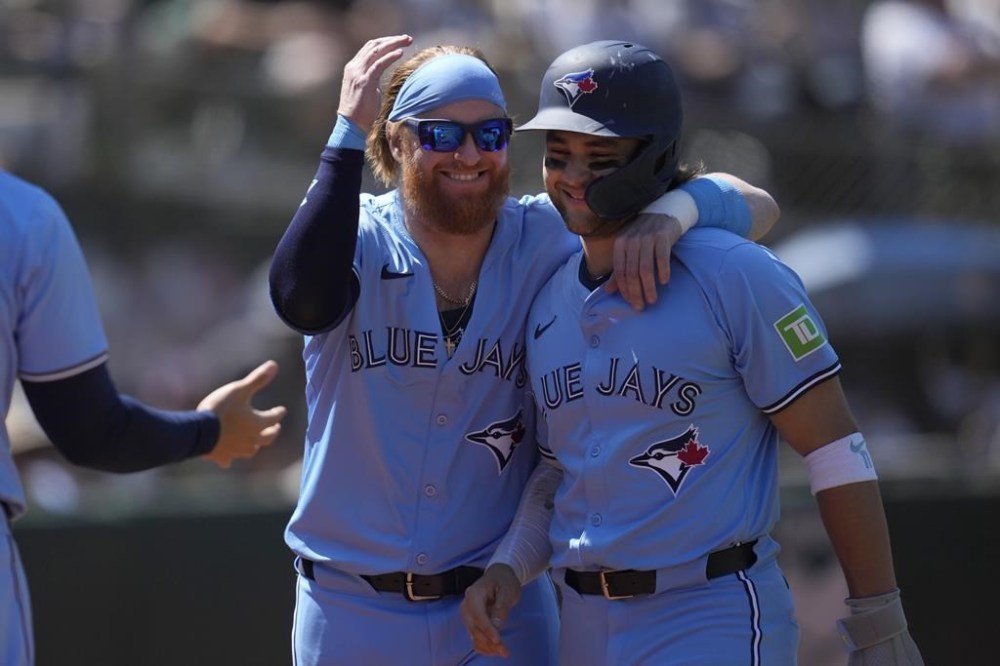 Toronto Blue Jays' Justin Turner, left, celebrates with Bo Bichette after both scored on a three run-double hit by Isiah Kiner-Falefa during the 10th inning of a baseball game against the Oakland Athletics in Oakland, Calif., Sunday, June 9, 2024. (AP Photo/Jeff Chiu)