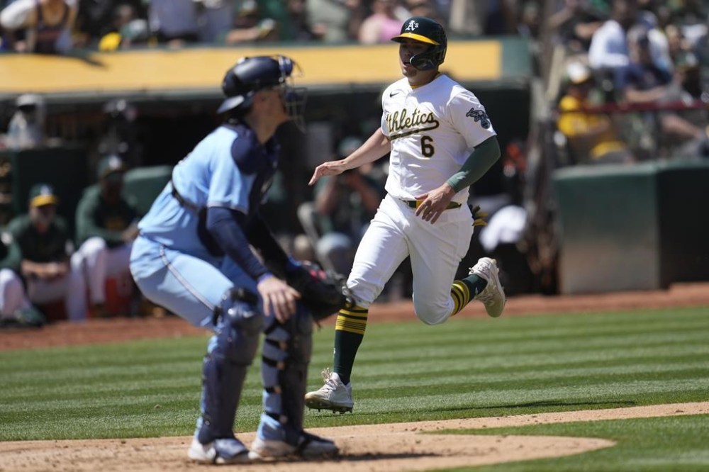 Oakland Athletics' Aledmys Díaz (6) runs home to score next to Toronto Blue Jays catcher Danny Jansen during the seventh inning of a baseball game in Oakland, Calif., Sunday, June 9, 2024. (AP Photo/Jeff Chiu)