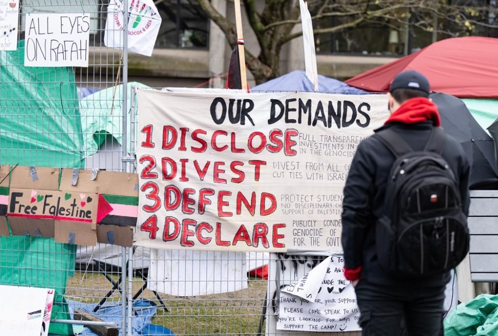McGill University is proposing to review its investment in weapons manufacturers and grant amnesty to protesting students as part of a new offer to members of a pro-Palestinian encampment on its Montreal campus. A man reads a sign of demands posted outside a pro-Palestinian encampment set up on McGill University's campus in Montreal, Tuesday, April 30, 2024. THE CANADIAN PRESS/Christinne Muschi