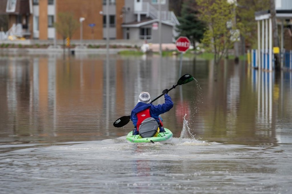 The Quebec government estimates that the number of homes located in flood zones could triple in the province when new flood maps are released. A resident uses a kayak to make their way through flooding in the Gatineau region of Gatineau, Que., on Thursday, May 4, 2023. THE CANADIAN PRESS/Spencer Colby