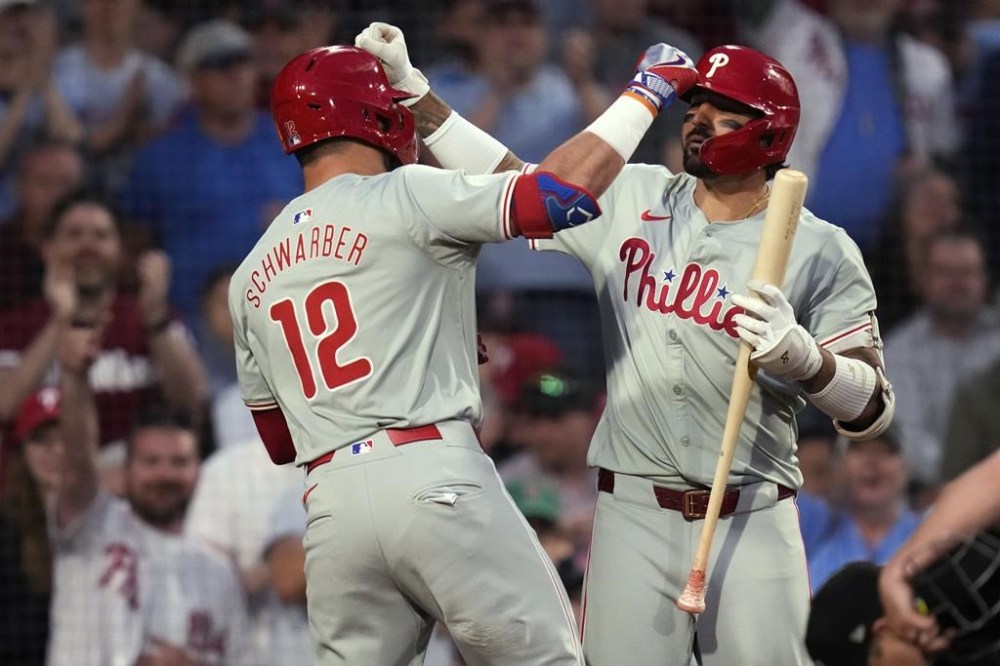 Philadelphia Phillies' Kyle Schwarber (12) is congratulated by Nick Castellanos after his solo home run against the Boston Red Sox during the fifth inning of a baseball game Tuesday, June 11, 2024, in Boston. (AP Photo/Charles Krupa)