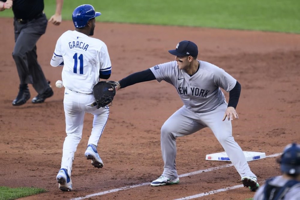 Kansas City Royals' Maikel Garcia (11) is safe at first as the throw to New York Yankees first baseman Anthony Rizzo, right, by shortstop Anthony Volpe hits Garcia during the third inning of a baseball game Tuesday, June 11, 2024, in Kansas City, Mo. (AP Photo/Reed Hoffmann)