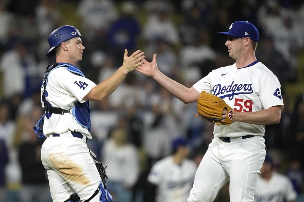 Los Angeles Dodgers catcher Will Smith, left, and relief pitcher Evan Phillips congratulate each other after the Dodgers defeated the Texas Rangers 15-2 in a baseball game Tuesday, June 11, 2024, in Los Angeles. (AP Photo/Mark J. Terrill)