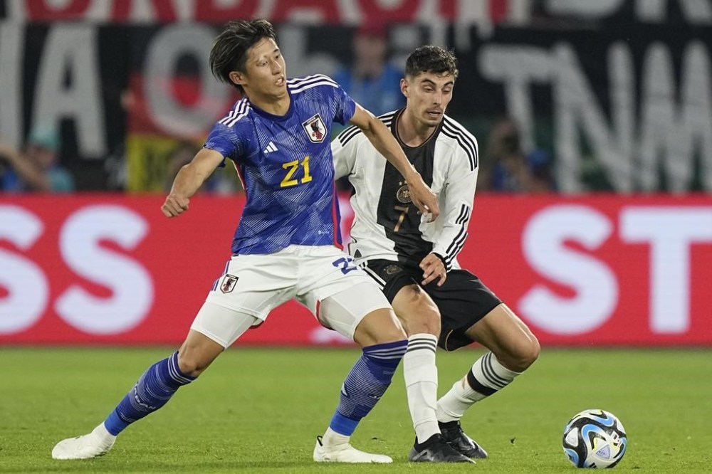FILE - Japan's Hiroki Ito is challenged by Germany's Kai Havertz, right, during an international friendly soccer match between Germany and Japan in Wolfsburg, Germany, Saturday, Sept. 9, 2023. Bayern Munich has signed Japan defender Hiroki Ito from German rival Stuttgart in a move which is expected to mark the start of a wider overhaul of Bayern’s squad. (AP Photo/Martin Meissner, File)